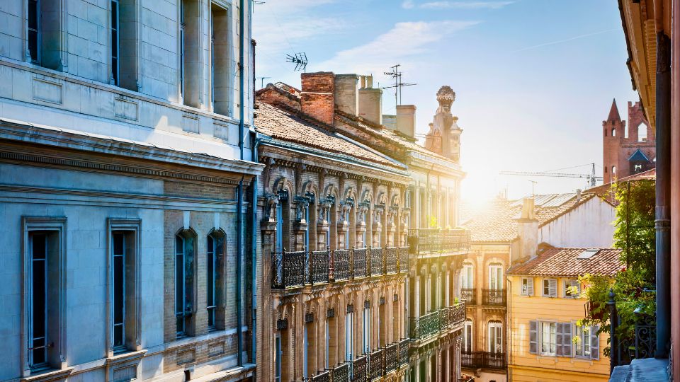 Vue ensoleillée des façades d'immeubles historiques à Toulouse Façades d'immeubles anciens dans une rue ensoleillée de Toulouse