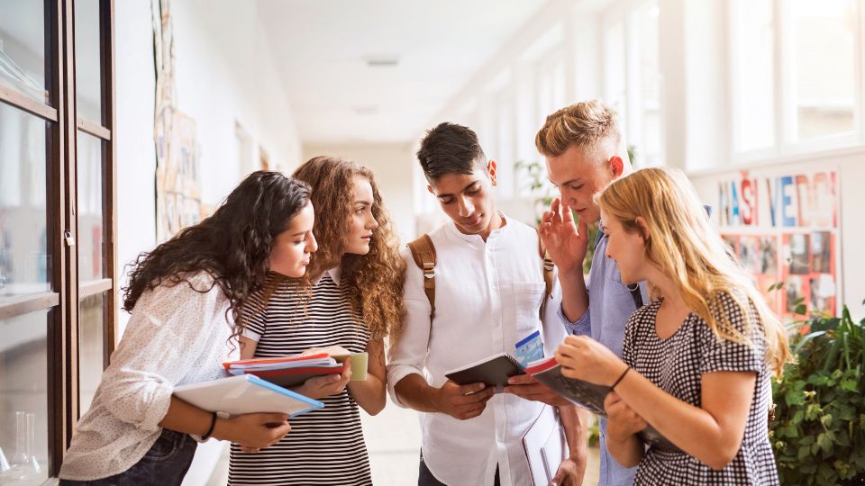 Étudiants à la recherche d'un logement dans un couloir d'université à Toulouse. Groupe d'étudiants discutant de logements ensemble dans un couloir lumineux.