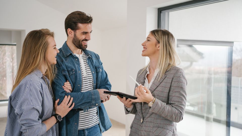 Couple en discussion avec une agent immobilier dans une maison Un couple discutant avec une agent immobilier à l'intérieur d'une maison